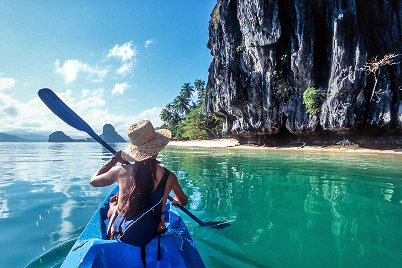 Sea-kayaking eco-traveller paddles through blue water in Palawan, El Nido, the Philippines