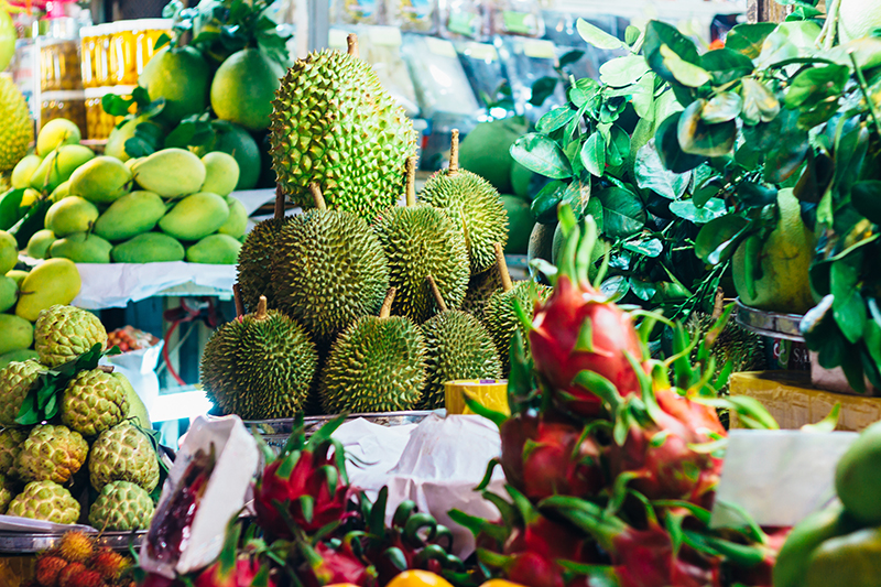 Mango, dragon fruit, durian, custard apples and oranges on a fresh fruit stall at the local market in Ho Chi Minh city, Vietnam;