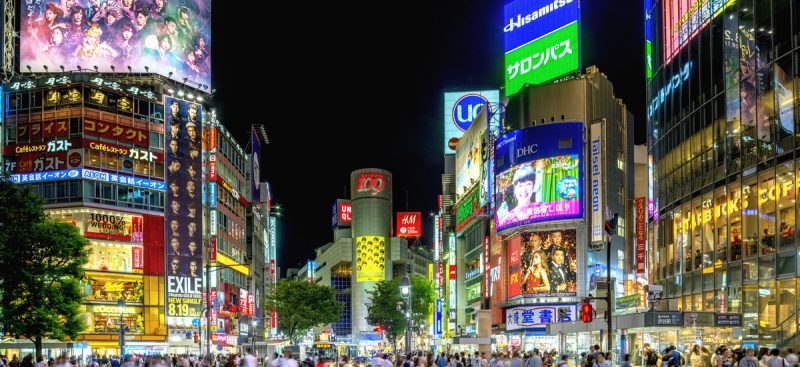 People crossing Shibuya crossing in Tokyo at night.